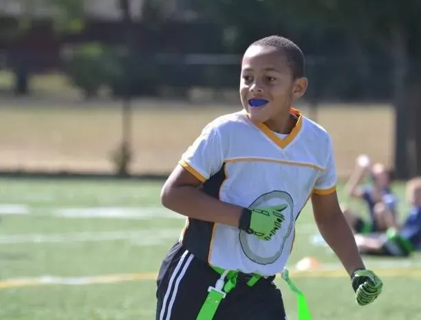 Youth athlete wearing a custom sports mouthguard provided by Great Smiles Buford Center in Buford GA before a football game